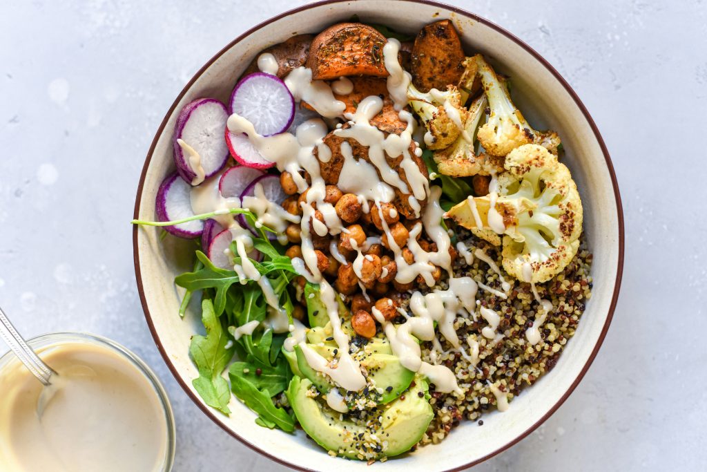 Bol nourrissant composé de quinoa,, avocat, radis, patate douce, chou-fleur et pois chiches rôtis