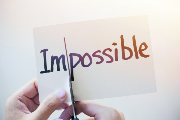Personne coupant le mot « impossible » pour suggérer la transformation des croyances et le changement d’habitudes. Image utilisée pour illustrer l'article intitulé "Pourquoi c’est si difficile de changer (et comment arrêter de se battre contre soi-même)"