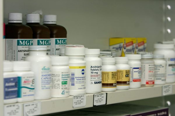 Étagère d’une pharmacie remplie de flacons de médicaments sur ordonnance, étiquetés et rangés côte à côte. Invitation à réfléchir aux bienfaits réels de la médecine moderne.
